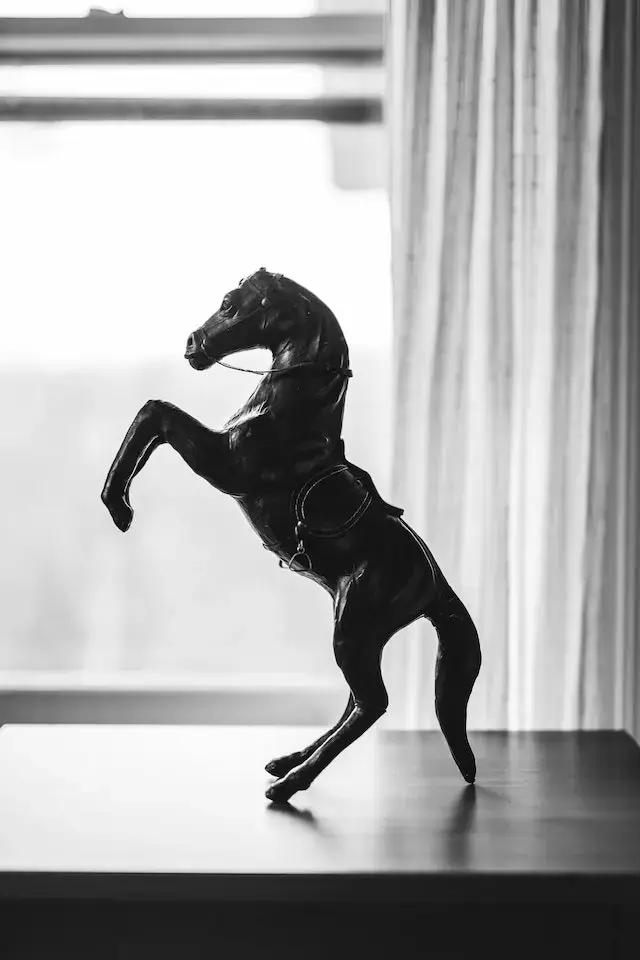 Black and White Picture of a Horse Figurine on a Wooden Surface.

Can we keep horse statues at home?
